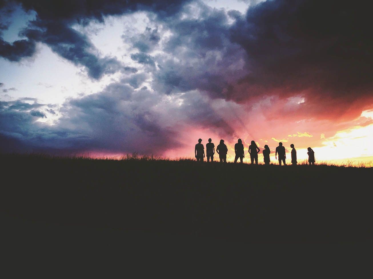 people on a hill with sunset